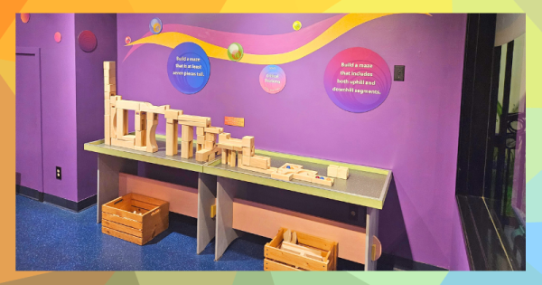 Two tables have wooden blocks of different sizes in front of a purple wall.